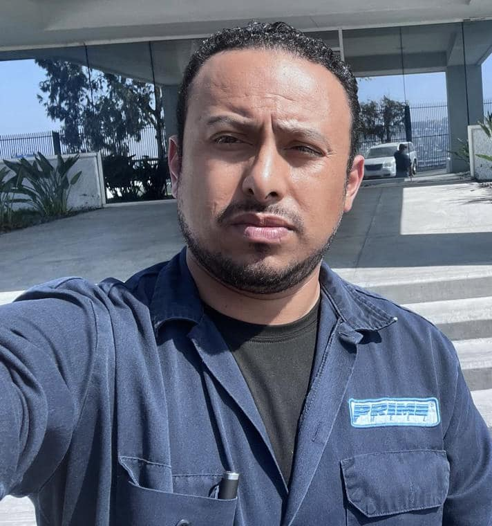 Foto de Servando Salazar Cano frente a la planta de Prime Wheel, donde fue visto por última vez el 23 de agosto de 2024. Lleva puesto el uniforme de trabajo azul con el logotipo de la empresa.